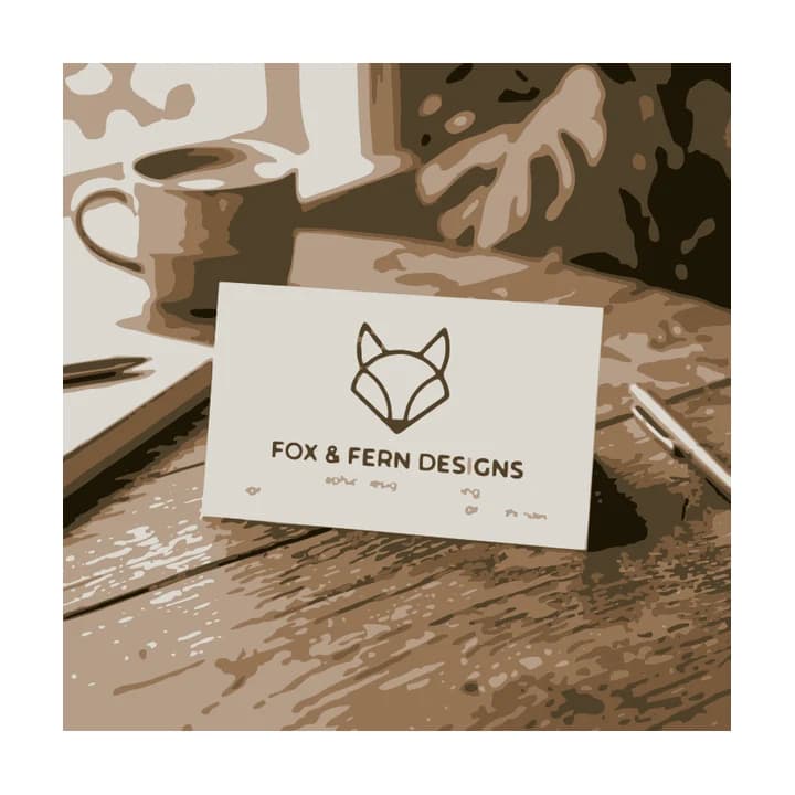 Vektorisierung eines Visitenkarten-Mockups: sepiafarbenes Bild von Schreibtisch, Tasse, Pflanze und Stiften, Fuchs und Fox & Fern Designs auf der Karte lesbar